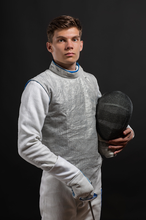 Portrait of Handsome Young male fencer wearing white fencing costume against Dark Backgroundの写真素材