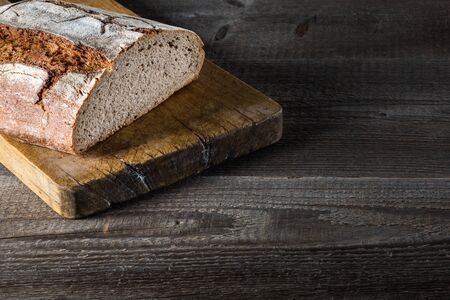 Sliced baked bread on cutting board; Rustic wooden table;の写真素材