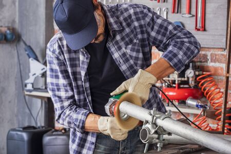 Metalworker working on three metal pipes during the manufacturing process on his workbench in an engineering workshop or factory in a close up viewの写真素材
