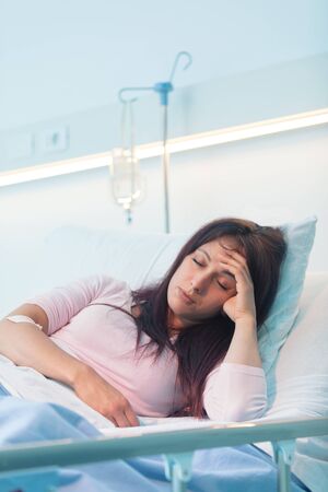 Young female patient lying in a hospital bed at night and she is sufferingの写真素材