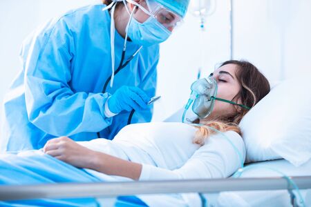 Doctor examining female patient in critical health conditions using a stethoscope in the intensive care unit of a modern hospital during covid-19 pandemic