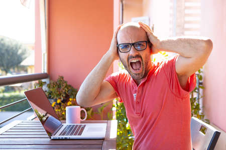 Young man studying and working on a project outdoor on his laptop is going crazy.