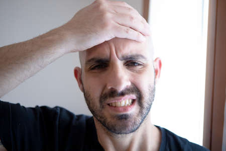 Stressed man. Frustrated young man touching his head with his hand. Headache concept. Stress conceptの写真素材