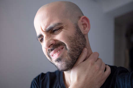 Caucasian young man with neck and shoulder pain. Auto massage for muscle injury. Isolated human. Neck therapy needed. Isolated human touching neck. Sore Spineの写真素材