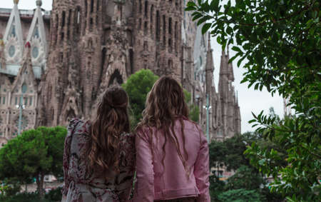 Pretty young girl relaxing sitting near by artificial lake and watching out to the Sagrada Familiay