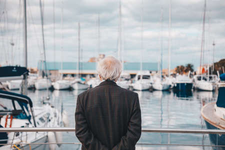 Old man with white hairs and well dressed looking the boats in the port harbor - Meditation lonely concept の写真素材