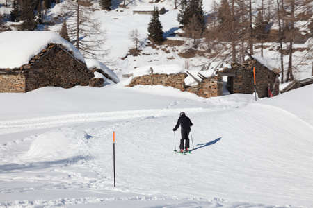 Isolated Skier skiing near a abandoned and snowy old cottage in mountain during the winter season.の写真素材