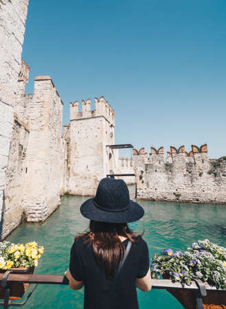 Girl with hat looking the Amazing Castle of Sirmione - Garda lake in a sunny day - Italyの写真素材