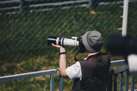 professional photographer with camera and telephoto lens in the filed taking photo of sports events.の写真素材