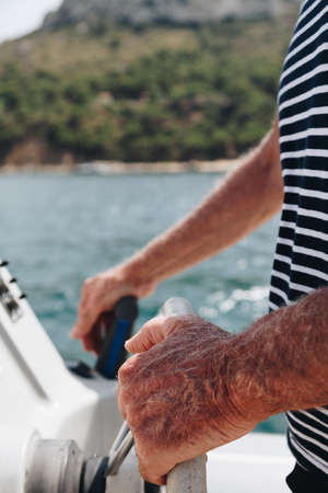 Close-up of Hand of Senior Captain on steering wheel of motor boat