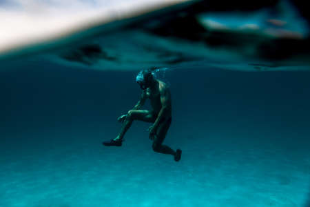 interesting under-water view of a Senior man floating on the ocean.