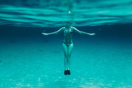 under-water relaxing view of a girl floating in the blue - Concentration and yoga concept.