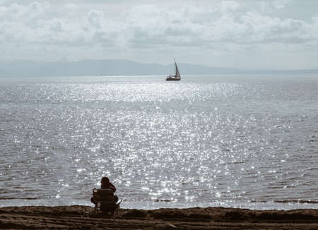 people looking the horizon over a calm sea with sail boat and blue cloudy sunny sky - peace relax concept.の写真素材
