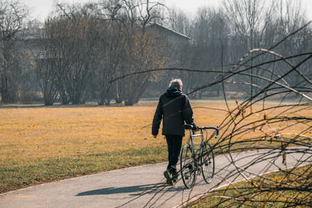 healthy old senior man walking at the park with his bikeの写真素材