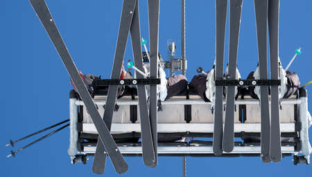 aerial bottom view of ski lift with skier with blue sky