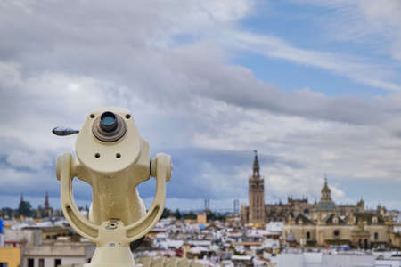 Telescope on the observation deck with view of Seville in a cloudy day - Spain capital of Andalusia