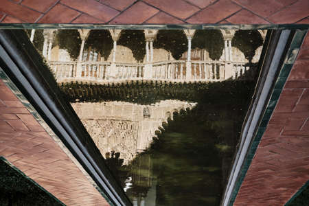 water reflection arch of courtyard of Royal Alcazar with plants - seville spain