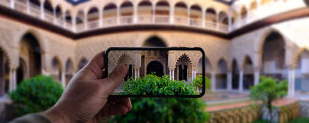 Man hand take a photo with smart phone to courtyard of Royal Alcazar with plants - seville spainのeditorial素材
