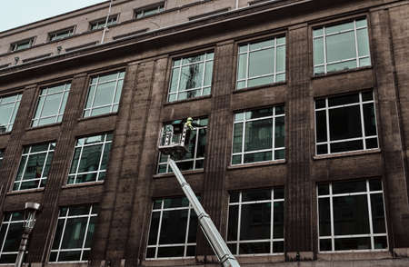 worker cleaning the windows of a building with a crane