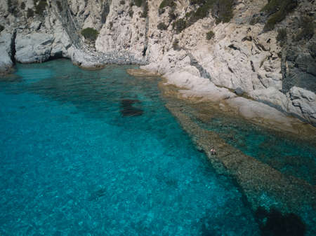 aerial view of sardinia shoreline with boat and crystal clear blue turquoise sea - (Cala Sirena)...