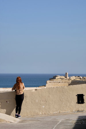 girl looking at the sea through the walls of the old city in the Valletta district of Maltaの写真素材