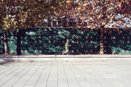 child walking and playing along a tree-lined avenue in the city centreの写真素材
