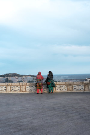 Two Indian women in traditional dress enjoy the panoramic view from Saint Remy Bastion in Cagliari, Sardiniaの写真素材