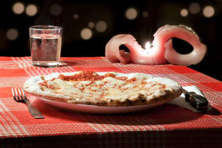 A margherita pizza on a table of a romantic pizzeriaの写真素材