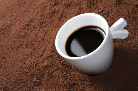 Espresso coffe cup on a bed of ground beansの写真素材