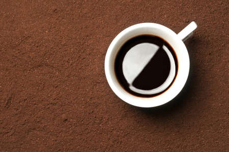 Espresso coffe cup on a bed of ground beansの写真素材