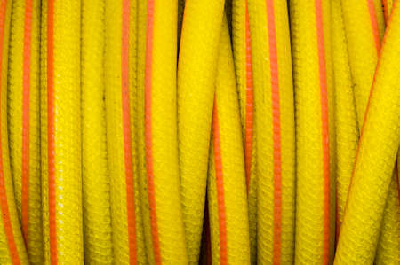 Yellow and orange water hose for watering gardensの写真素材