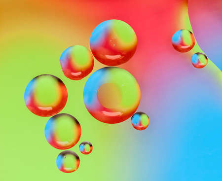 Oil drops on water surface lit from beneath.