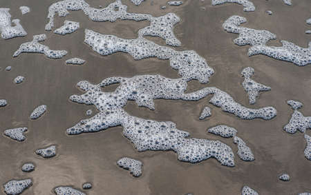 Colorful foam and bubbles induced by pollution in sea water on  beach