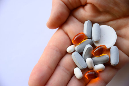 Hand offering group of blue, white and orange pills for healthcareの写真素材