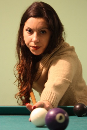 brown-haired caucasian girl plays billiards. the cue, the balls and the holes.