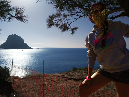 girl with gray sweatshirt enjoys nature among the trees and the land of Cala d'Hort in Ibiza and its bright colorsの写真素材