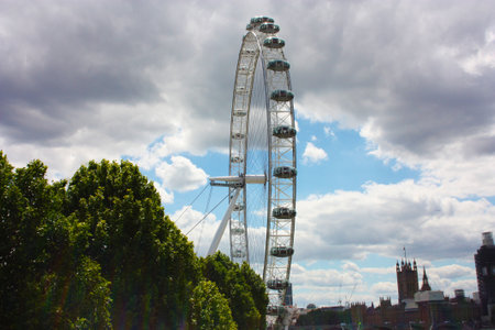 the british london eye of england on the river under a gray and cloudy spring skyのeditorial素材