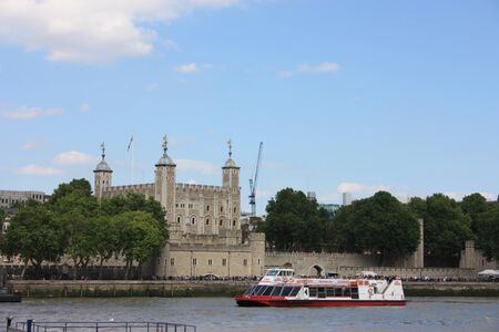 A tourist ferry transports tourists along the Thames river between the buildings and historic...