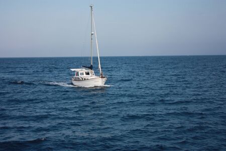 a white sailboat soaking in the summer blue water of the Mediterranean sea in spain