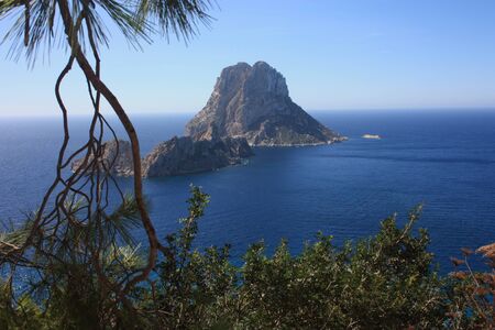 The magical island of Es Vedra with the small islet of Es Vedranell next to it in front of the coast of Cala d'Hort in the tourist island of Ibiza in the midst of nature between cliffs, beaches and coasts in spainの写真素材