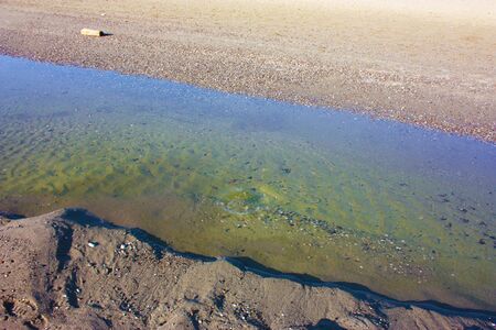 puddle of water in the sand by the seaの写真素材