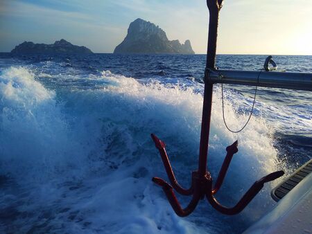 rocky islet of Es Vedra between sky and blue sea and white foam in the mist of Ibiza view from the...