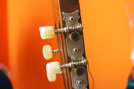 headstock with mechanics of a classical guitar with bright orange background