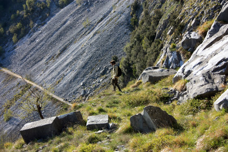 in search of buried treasures with the metal detector in a steep path between the peak of the rocky and green mountains in summerのeditorial素材
