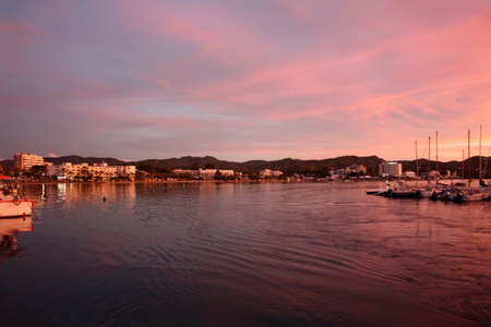 romantic pink sunset over the sea waters of the port of san antonio in ibiza in balearic islands