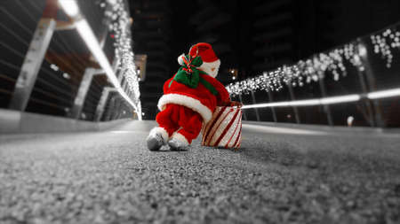 Santa Claus puppet looks tired of delivering presents for Christmas is walking a very long way lit with Christmas lights smallの写真素材