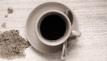 Toned image of cup of black coffee and spot of coffee on wooden tableの写真素材