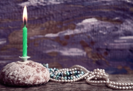 Toned image, burning candle, cake, pearls, purple backgroundの写真素材