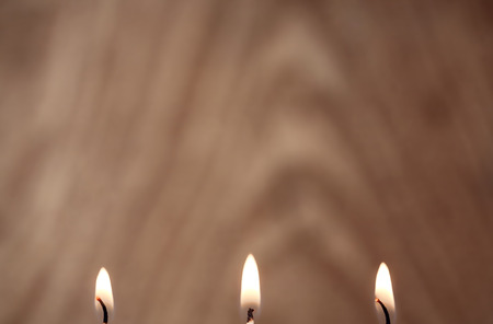 Three burning candles, wooden backgroundの写真素材