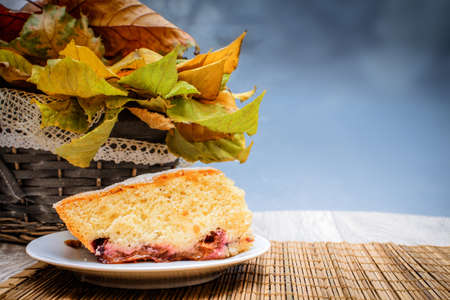 A piece of sponge cake bread on a straw bedding on a background of autumn leaves of a small...